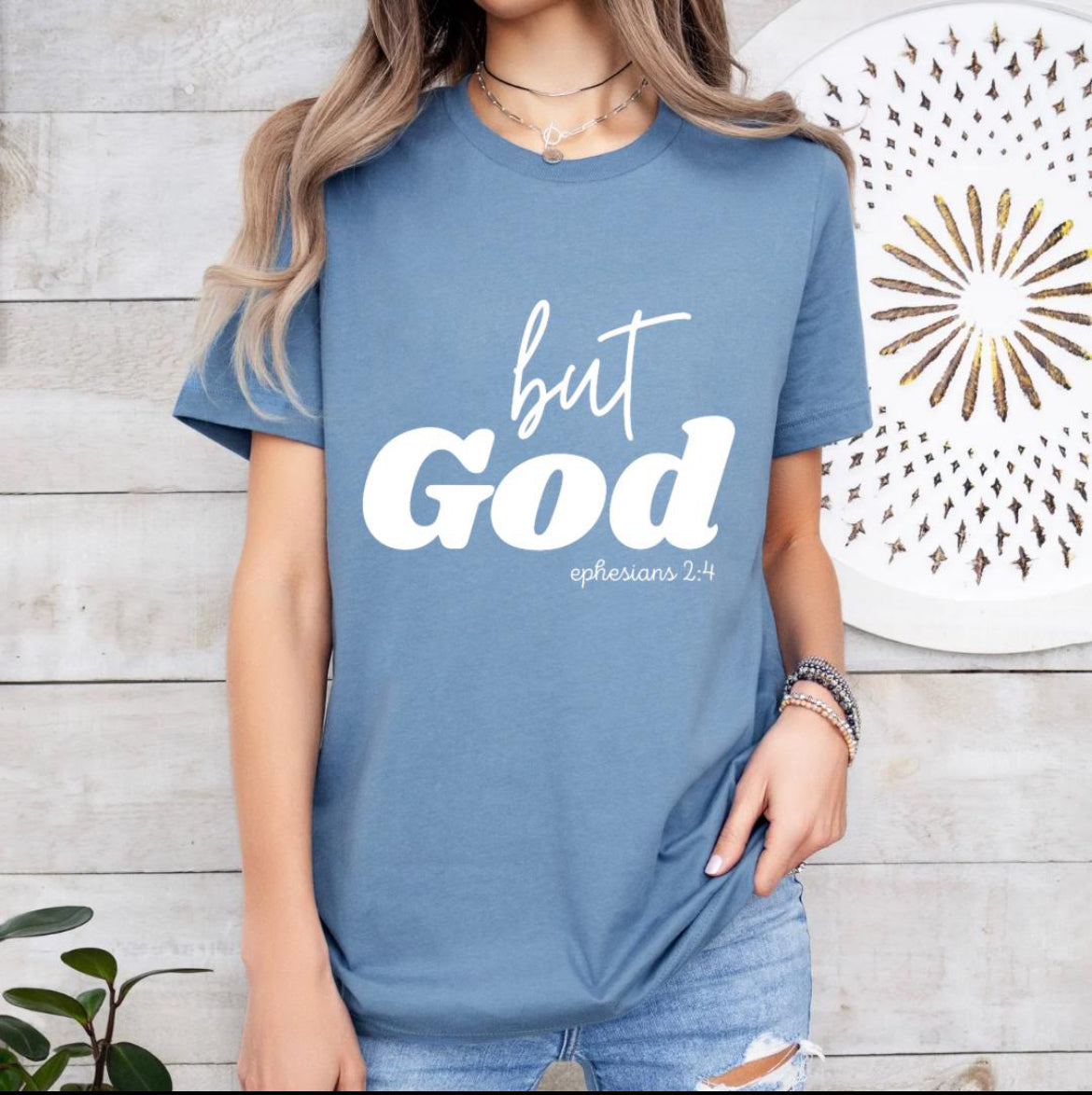 Steel blue crewneck t-shirt that says, “but God” in large letters. Underneath in smaller letters it says, “Ephesians 2 4.”