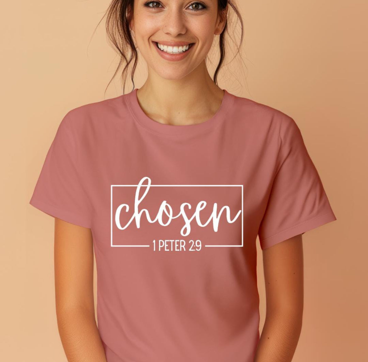 Mauve crewneck t-shirt that says, “chosen” in large cursive letters. Underneath in smaller letters it says, “1 Peter 2 9.”