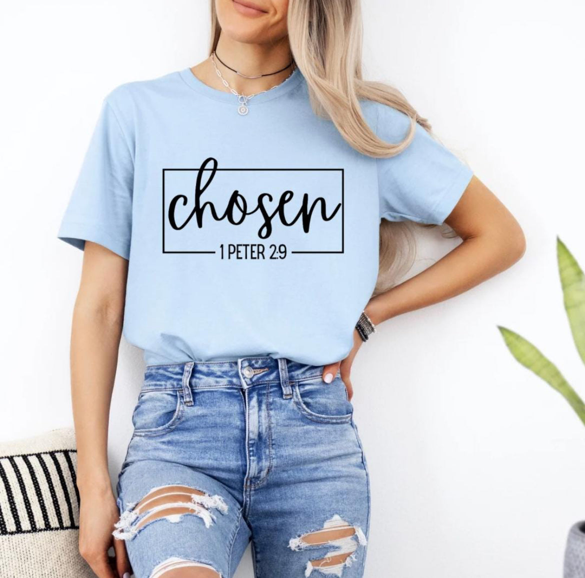 Baby blue crewneck t-shirt that says, “chosen” in large cursive letters. Underneath in smaller letters it says, “1 Peter 2 9.”