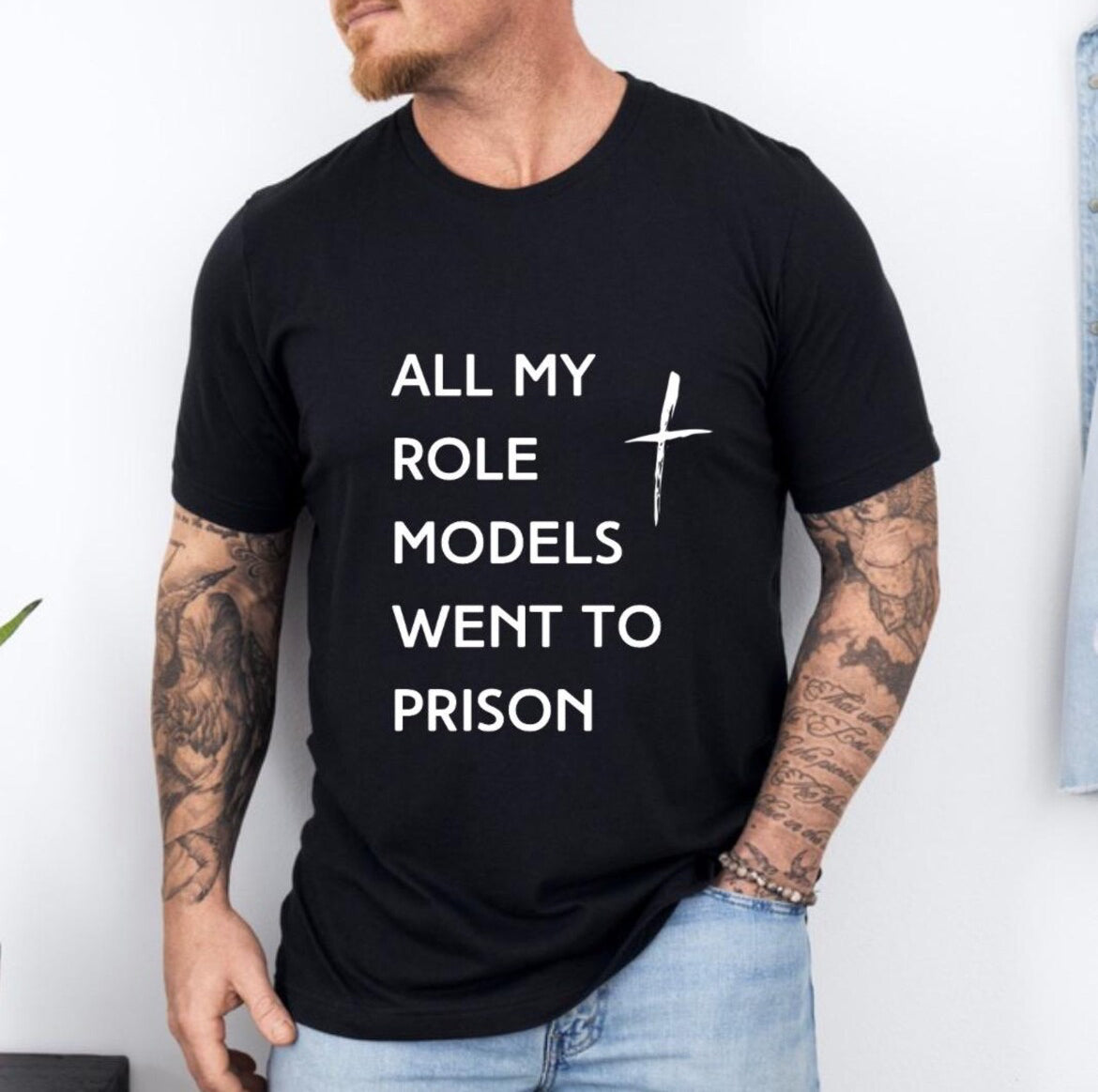 Black crewneck t-shirt that says, “all my role models went to prison” with a cross.