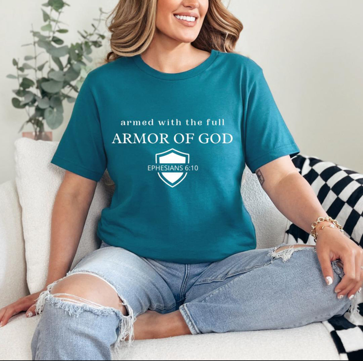 Deep teal crewneck t-shirt that says, “armed with the full armor of God.” There is a shield with “Ephesians 6 10” running through the middle.