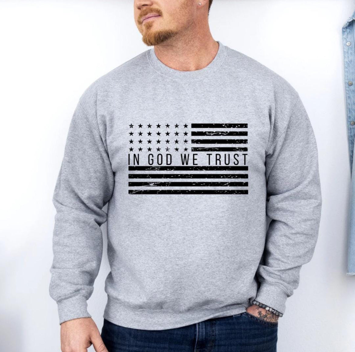 Light gray crewneck sweatshirt with a distressed American flag that says, "In God we trust" across the middle of the flag.