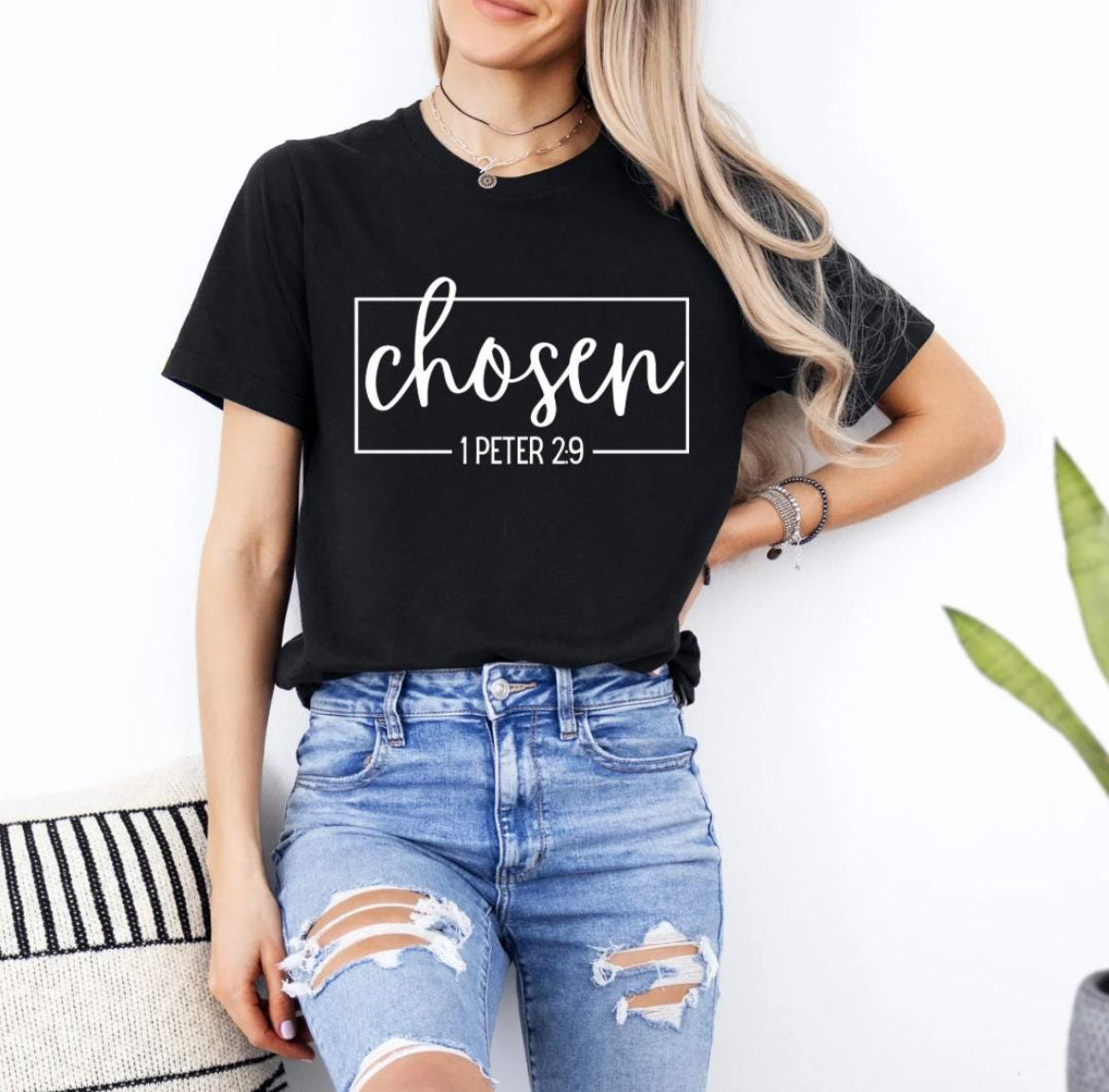 Black crewneck t-shirt that says, “chosen” in large cursive letters. Underneath in smaller letters it says, “1 Peter 2 9.”