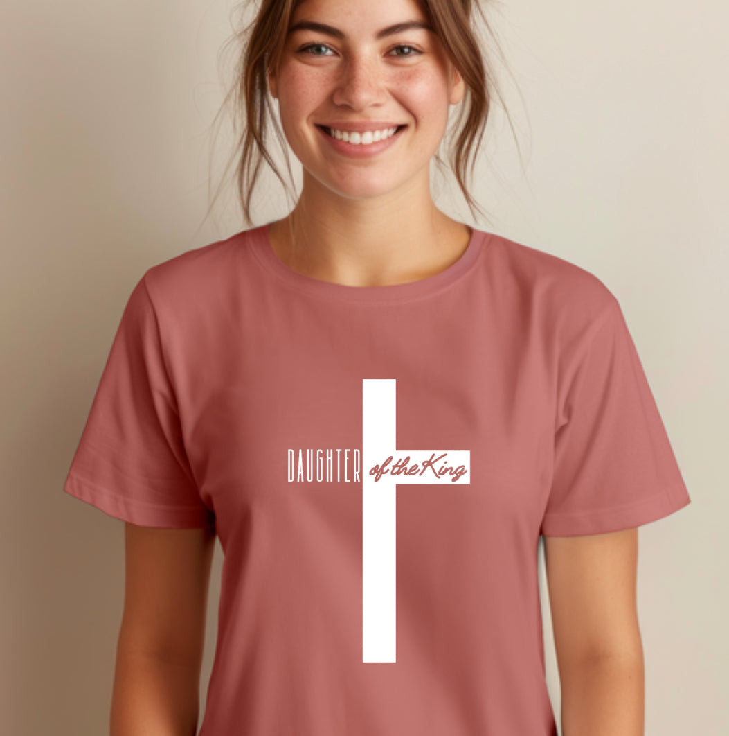 Mauve crewneck t-shirt that says, “Daughter of the King” running through a cross.