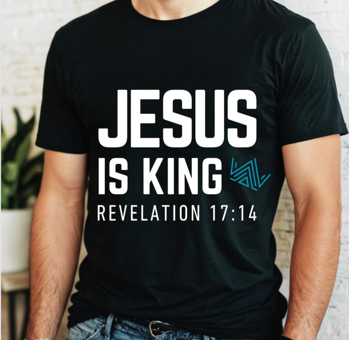 Black crewneck t-shirt that says, “Jesus is king” in large bold letters. There is a teal geometrical crown. Underneath in smaller letters it says, “Revelation 17 14”.