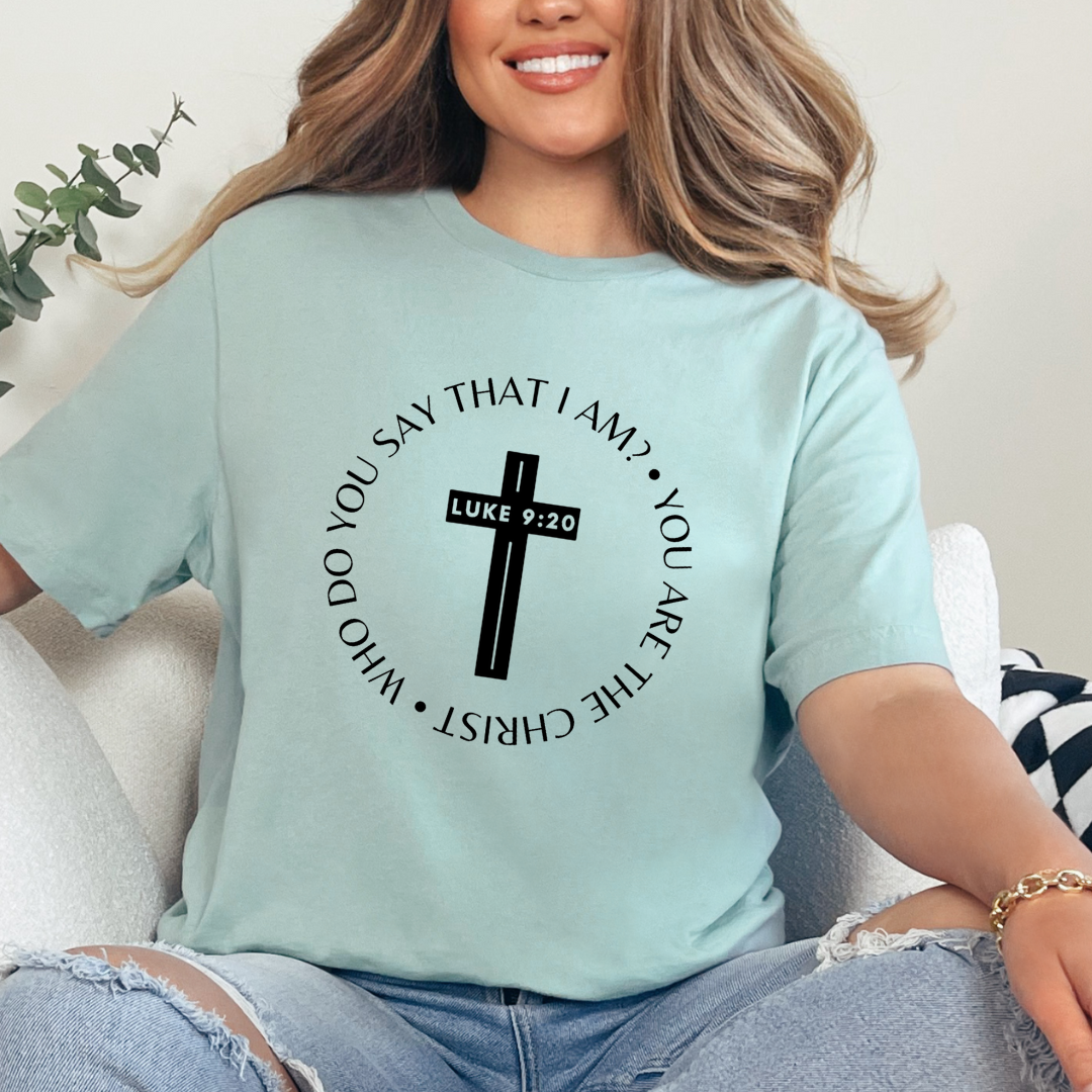 Dusty green crewneck t-shirt that says, “who do you say that I am? you are the Christ?” With a cross that says, “Luke 9:29” through the middle.