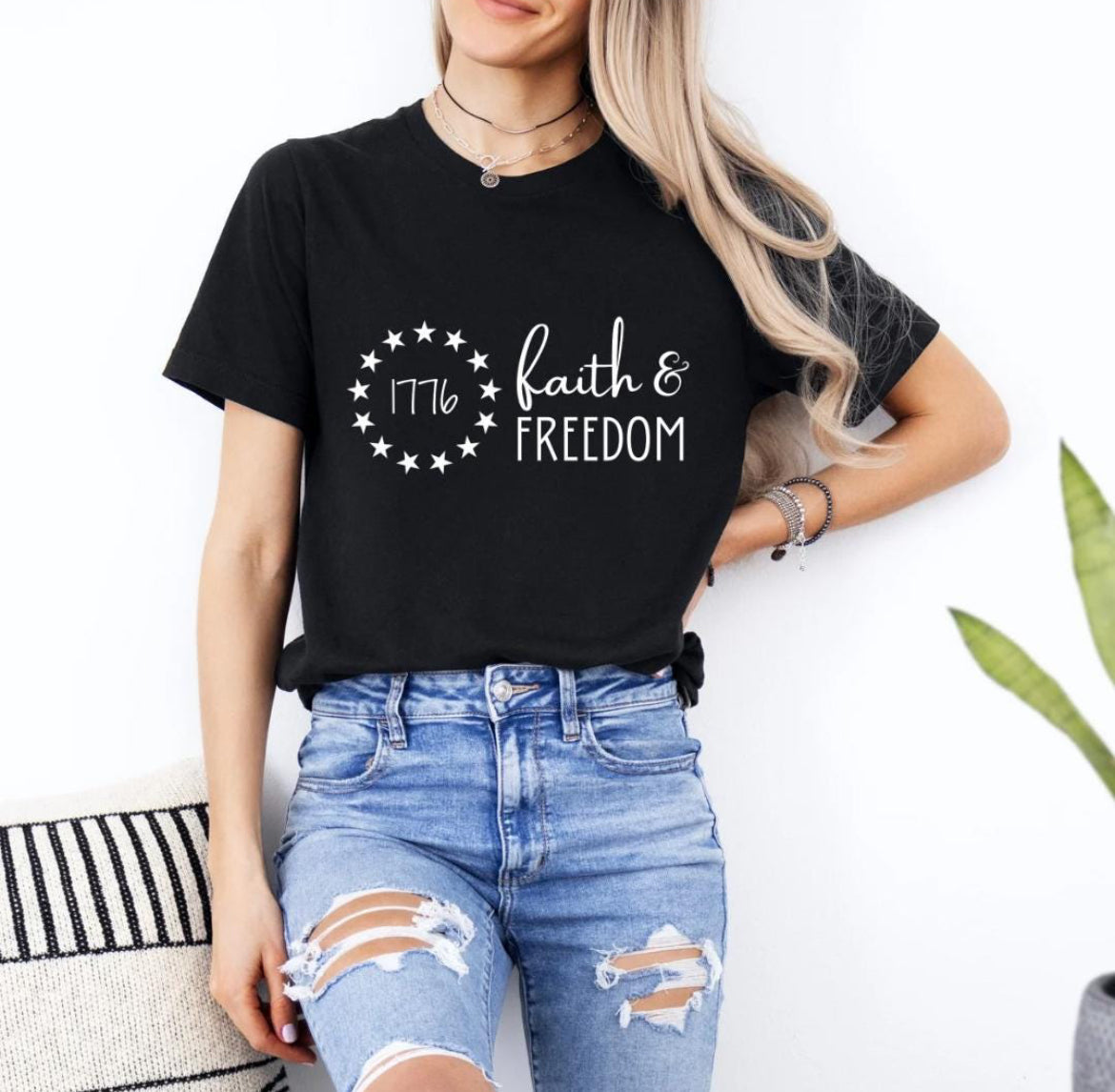 Black crewneck t-shirt that says, “Faith and freedom.” There is a Betsy Ross flag stars symbol with “1776” in the middle.