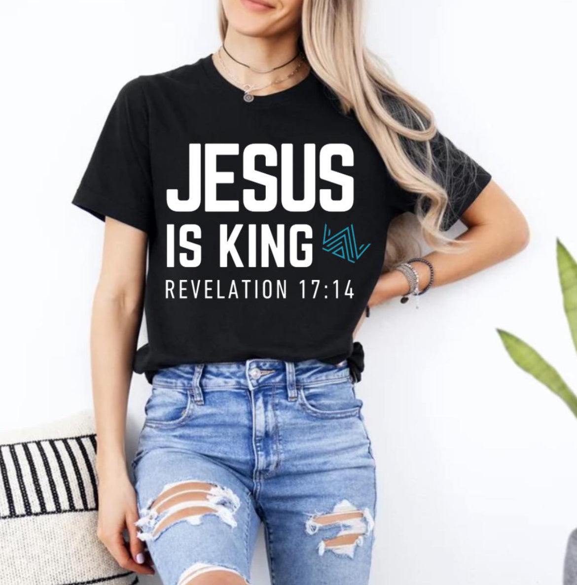 Black crewneck t-shirt that says, “Jesus is king” in large bold letters. There is a teal geometrical crown. Underneath in smaller letters it says, “Revelation 17 14”.