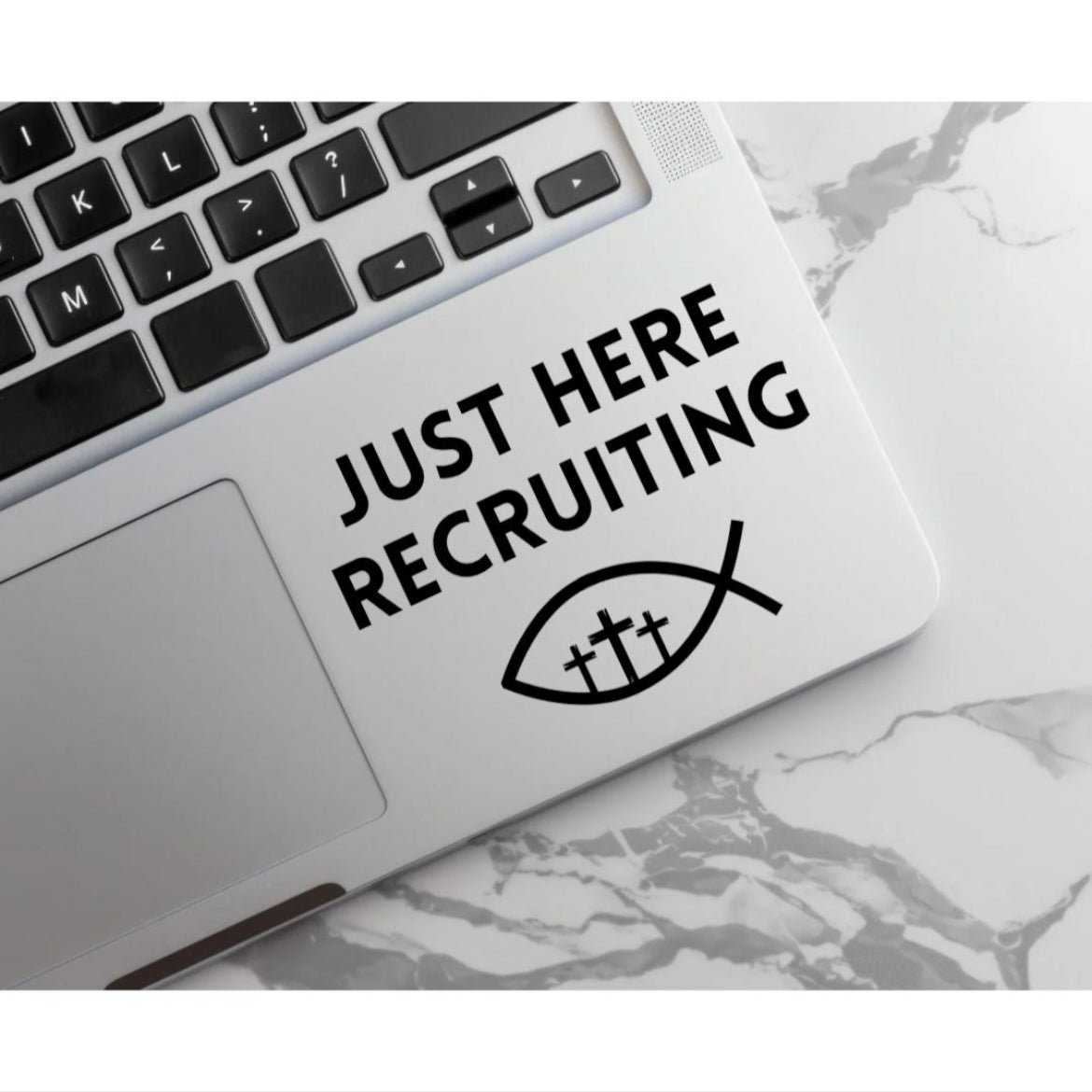 Laptop keyboard sticker that says, “Just here recruiting” with the ichthus fish symbol with three crosses in the middle.