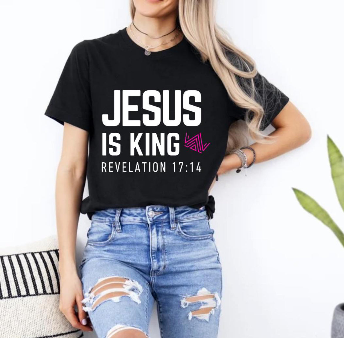 Black crewneck t-shirt that says, “Jesus is king” in large bold letters. There is a hot pink geometrical crown. Underneath in smaller letters it says, “Revelation 17 14”.
