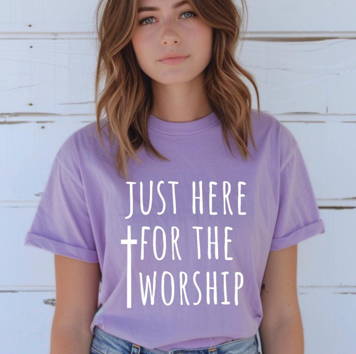 Lavender crewneck t-shirt that says, “just here for the worship” with a cross on it. On the back it has a small logo with a sun that says, “LTW”
