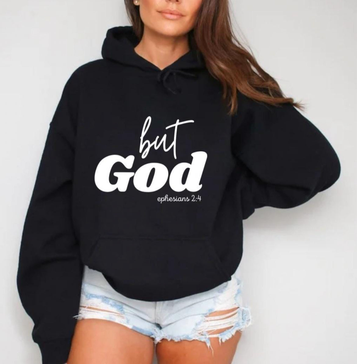 Black hooded sweatshirt that says, "But God" in large letters. Underneath it says, "Ephesians 2 verse 4" in smaller letters.