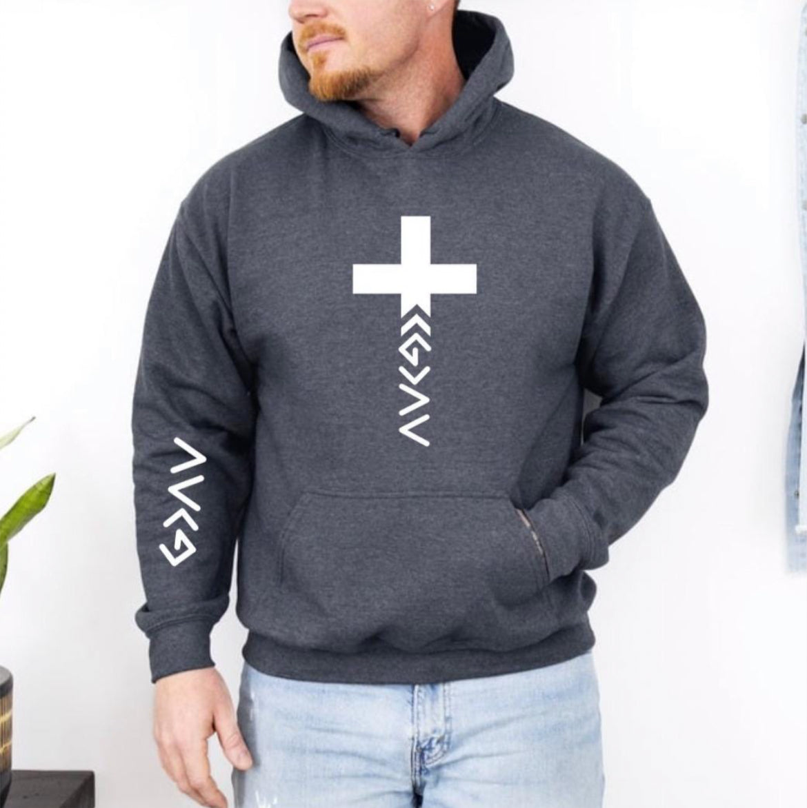 Dark gray hoodie that has a cross with the "God is greater than the highs and lows" symbol on the bottom. The same symbol is on the sleeve.