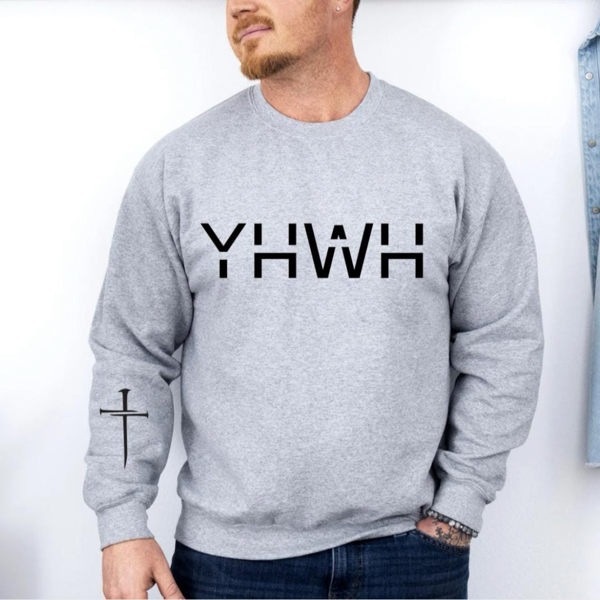 Light grey crewneck sweatshirt that says, "YHWH" with a cross on the sleeve.