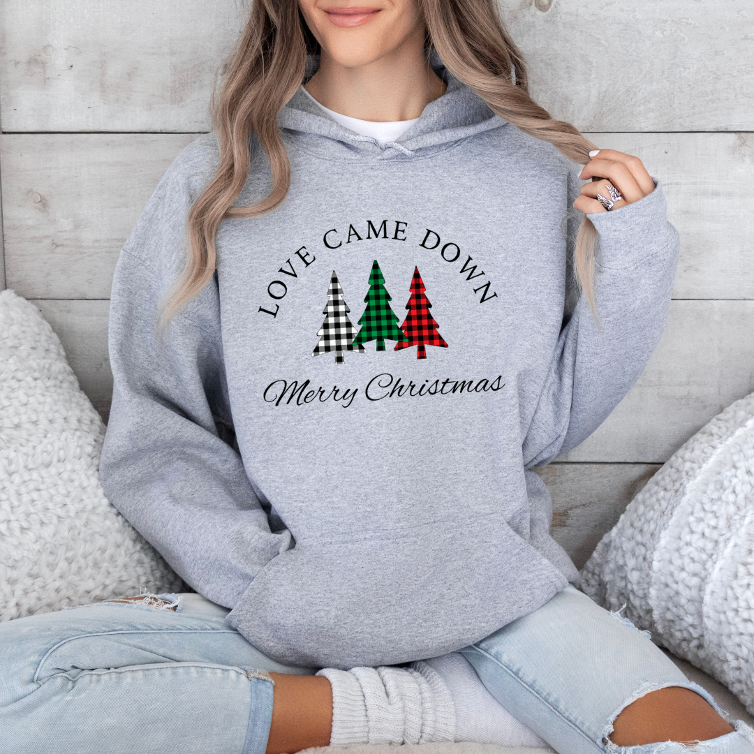 Grey hoodie sweatshirt that says, "Love came down. Merry Christmas" with three Christmas trees in buffalo plaid green, red and black.