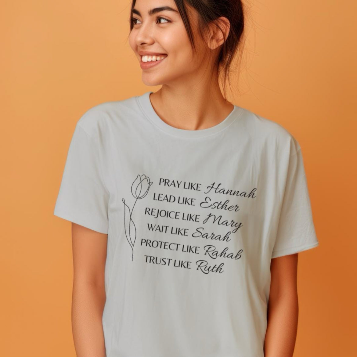 Grey crewneck t-shirt that says, “Pray like Hannah, lead like Esther, rejoice like Mary, wait like Sarah, protect like Rahab, trust like Ruth.”