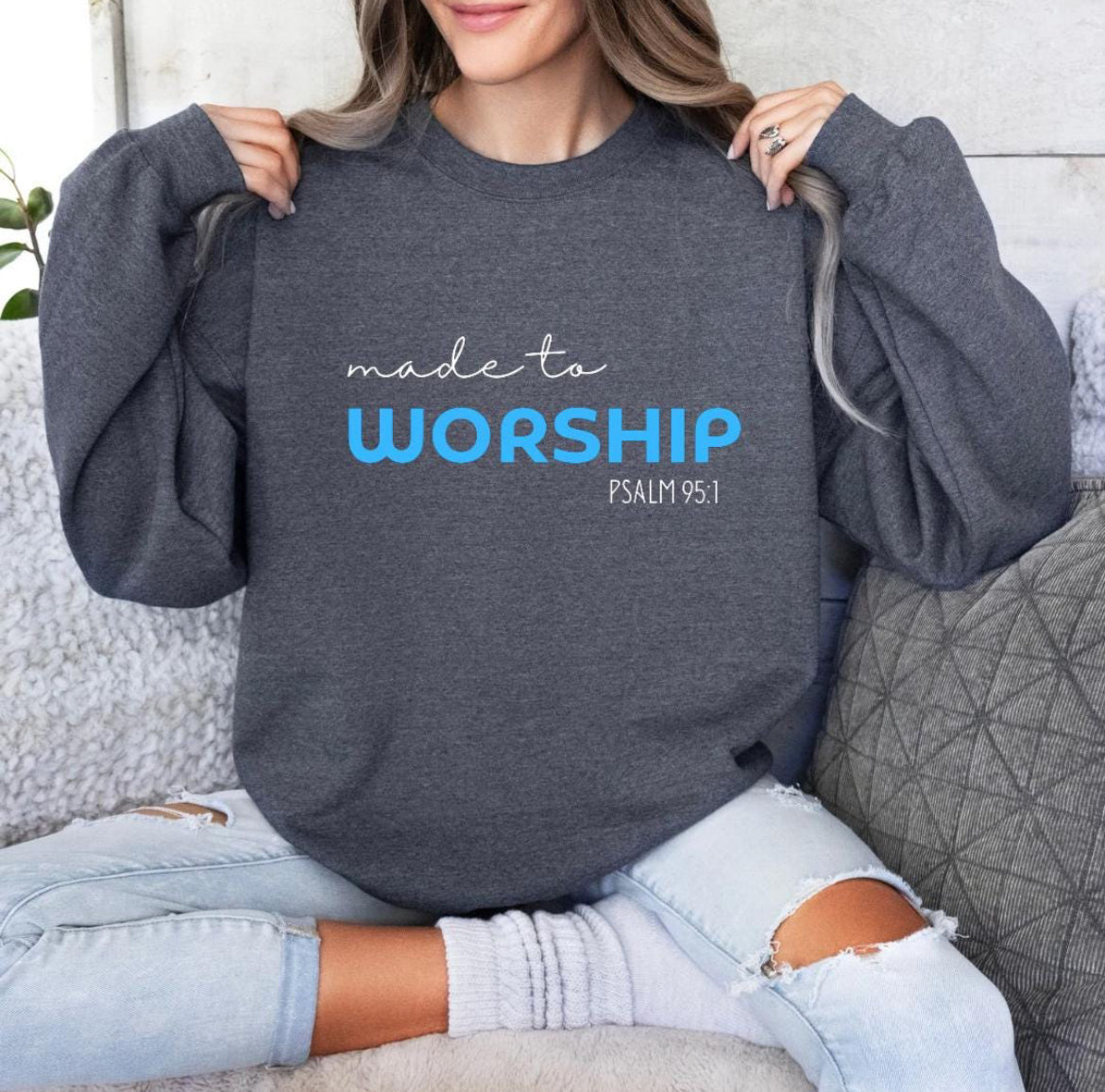 Dark gray crewneck sweatshirt  that says, "Made to worship" where the word "worship" Is a bright blue. Underneath in smaller letters it says, "Psalm 95 1."