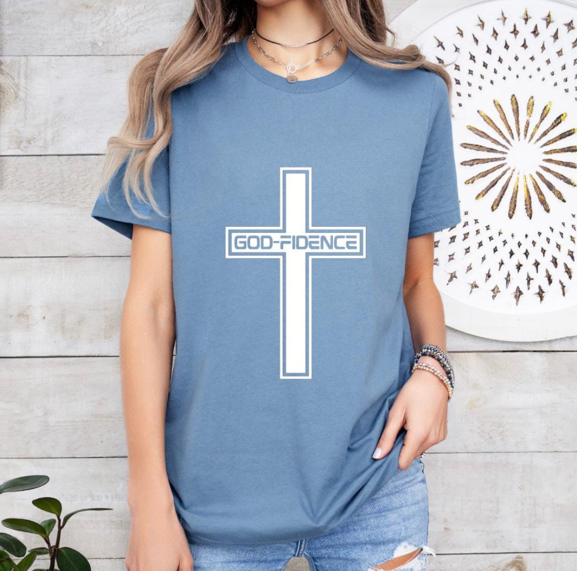 Steel blue crewneck t-shirt that says, “Godfidence” inside of a cross. 