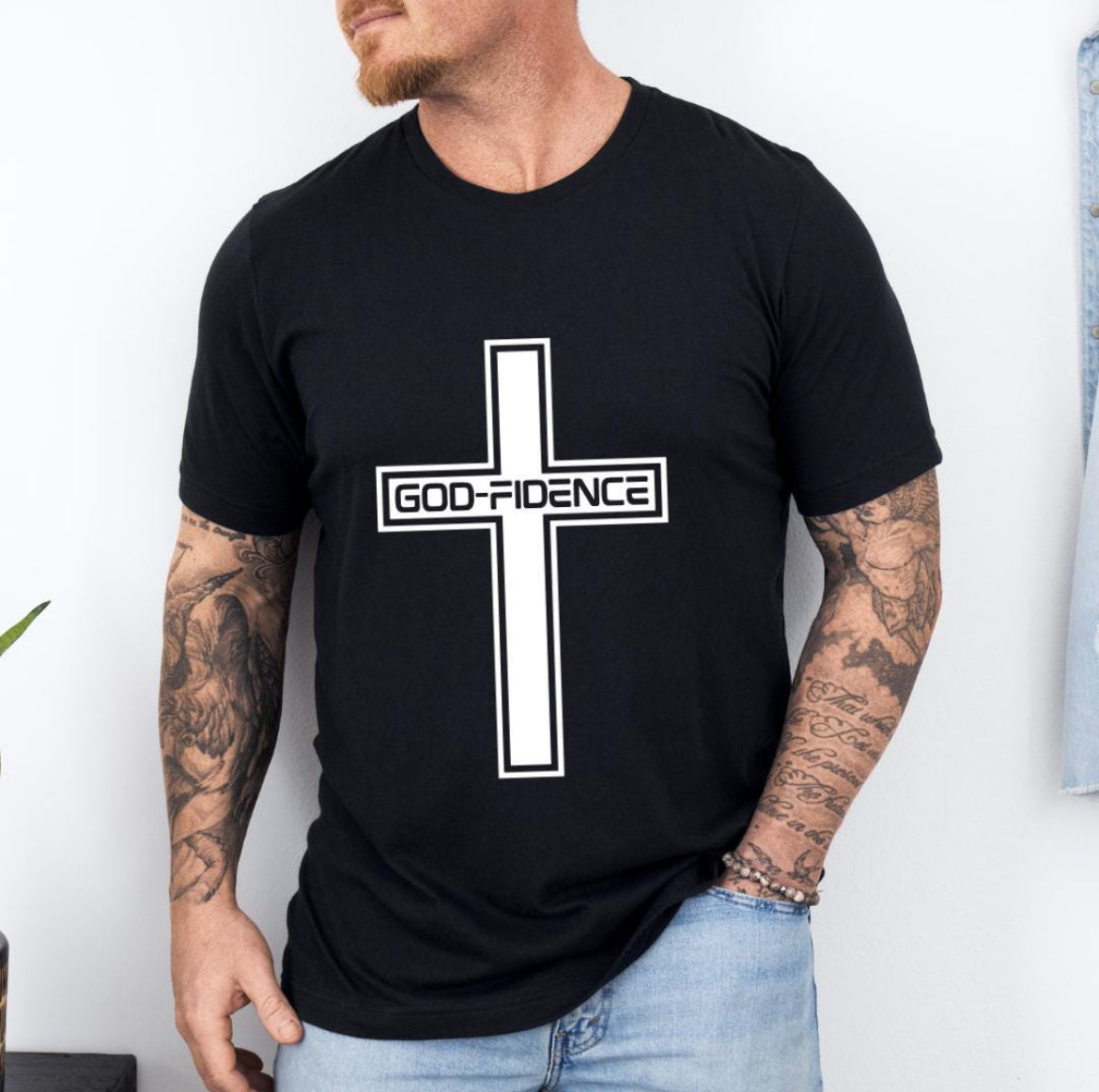 Black crewneck t-shirt that says, “Godfidence” inside of a cross. 