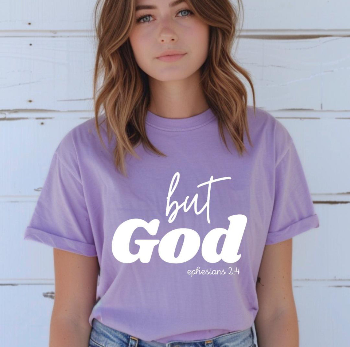 Lavender crewneck t-shirt that says, “but God” in large letters. Underneath in smaller letters it says, “Ephesians 2 4.”