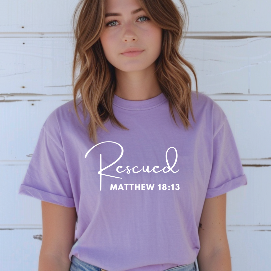 crewneck T-Shirt that says, "He left the 99 to rescue me". On the front it says, "Matthew 18:13 rescued" with a tan sheep.