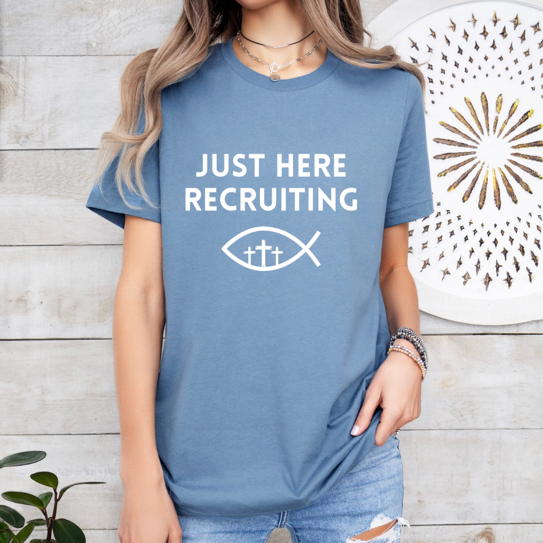 Steel blue crewneck t-shirt that says, “just here recruiting” with the ichthus fish symbol. In the middle of the fish are three crosses.