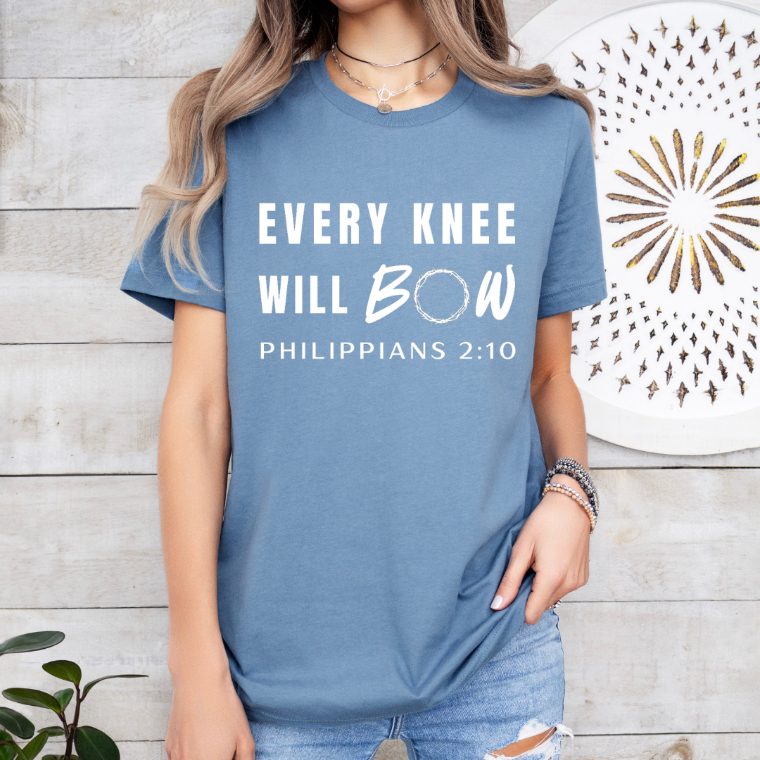 Steel blue crewneck t-shirt that says, “every knee will bow. Philippians 2:10” with a crown of thorns as the “o” in bow.