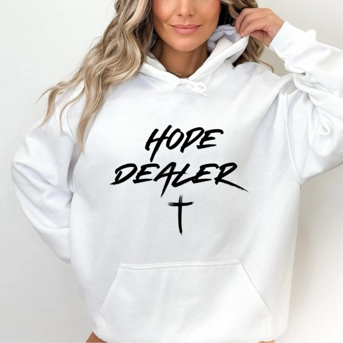 White hoodie sweatshirt that says, “Hope dealer” in graffiti style writing with a cross. 