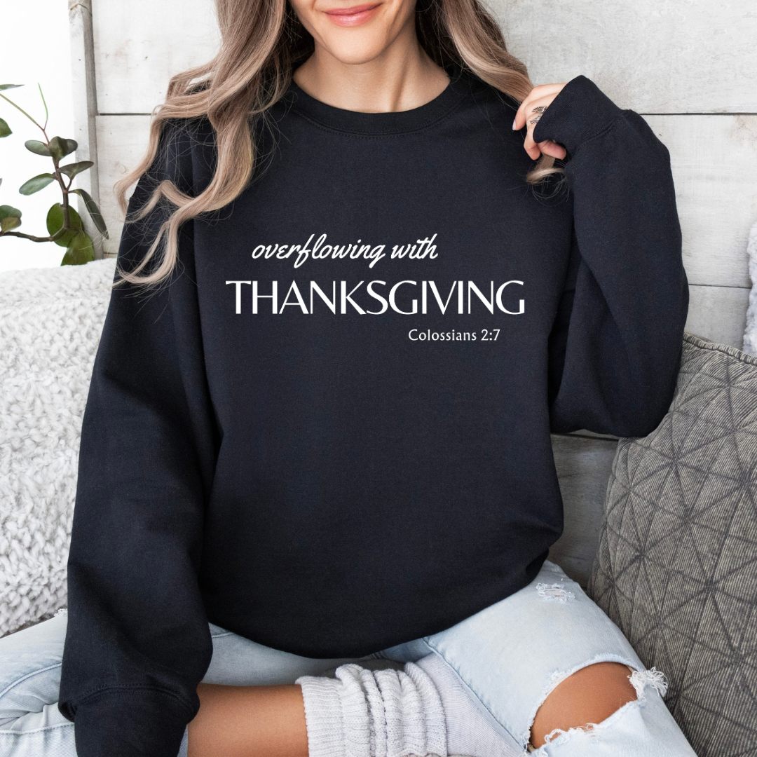 Black sweatshirt that says, “overflowing with Thanksgiving. Colossians 2:7.”