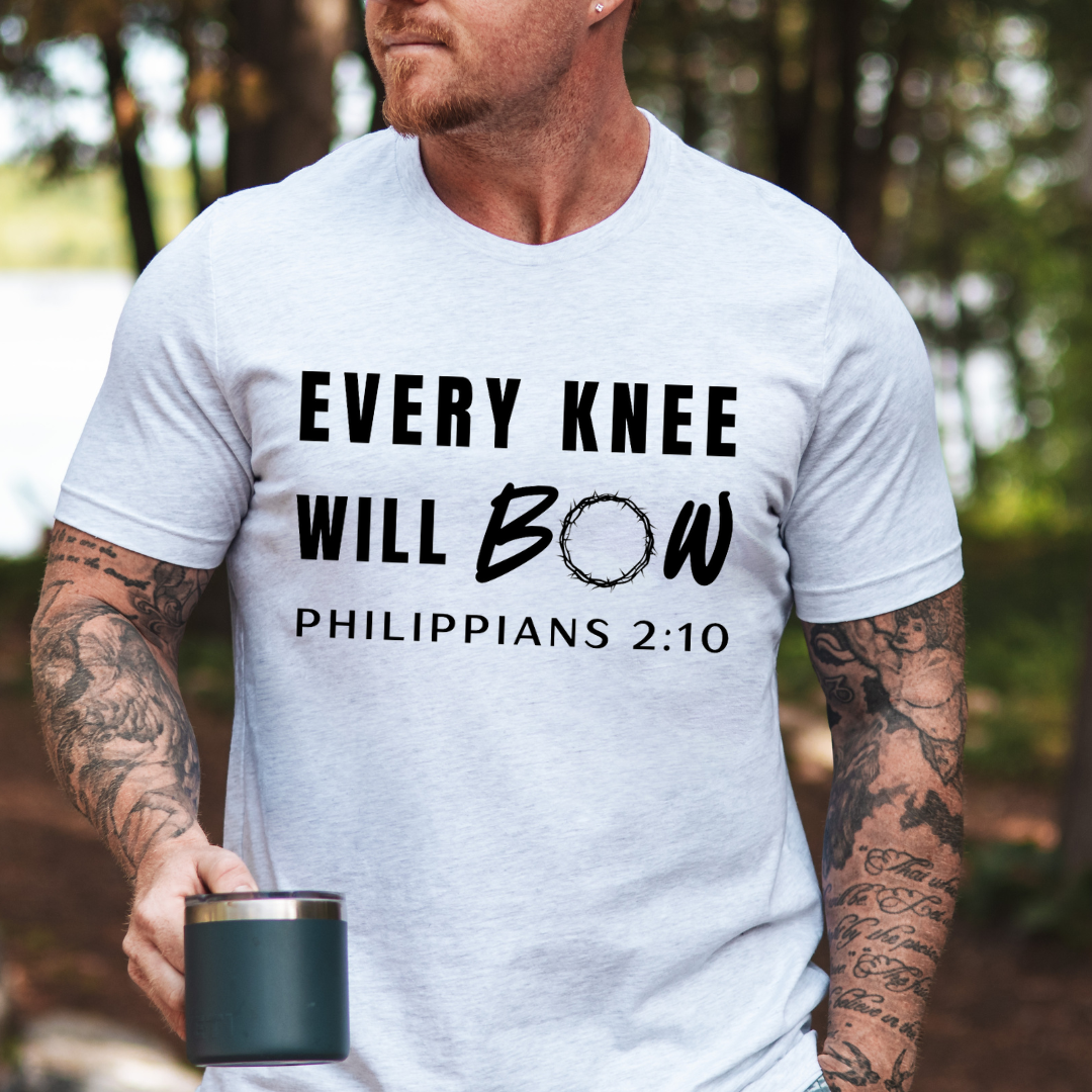 Ash white crewneck t-shirt that says, “every knee will bow. Philippians 2:10” with a crown of thorns as the “o” in bow.