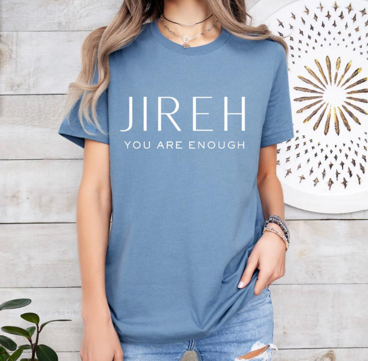 Steel blue crewneck t-shirt that says, “jireh” in large letters. Underneath it says, “you are enough.”