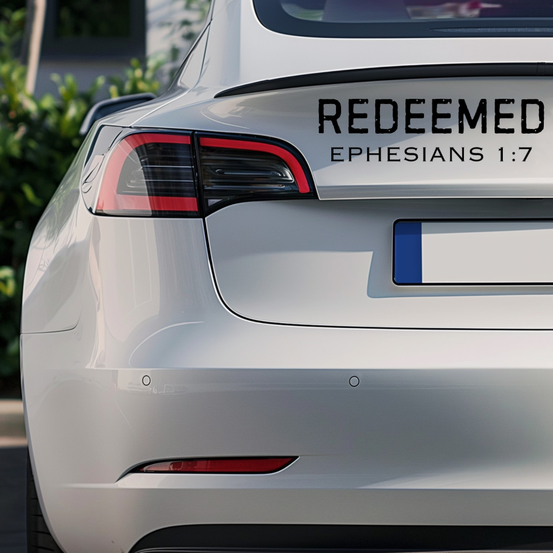 Bumper sticker car decal that says, “Redeemed” in large bold distressed letters. Underneath in smaller capital letters it says, “Ephesians 1 7.”