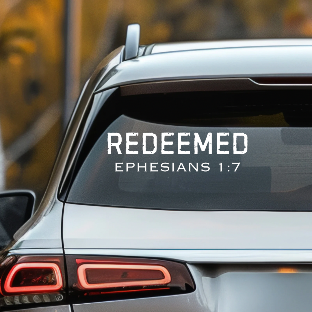 Car decal sticker that says, “Redeemed” in large bold distressed letters. Underneath in smaller capital letters it says, “Ephesians 1 7.”