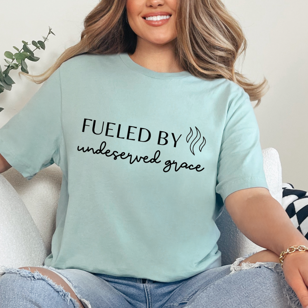 Dusty green crewneck t-shirt that says, “Fueled by undeserved Grace”.