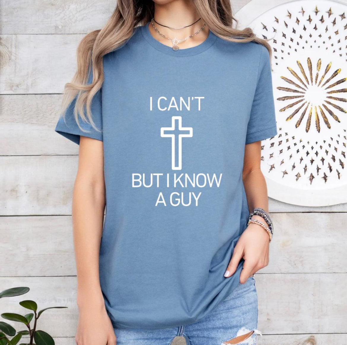 Steel blue crewneck t-shirt that says, “I can’t but I know a guy” with a cross in the middle.