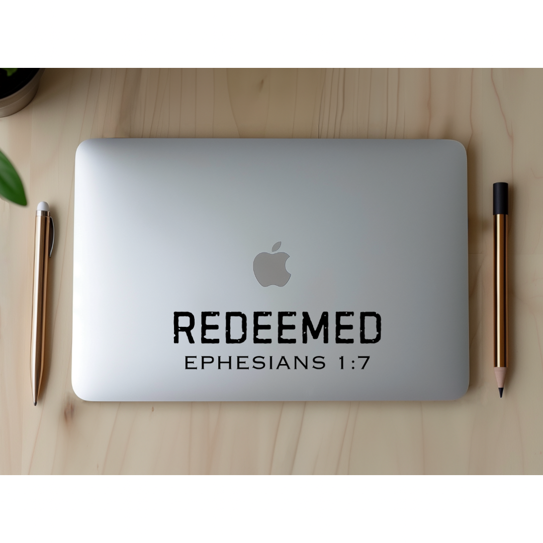 Laptop sticker decal that says, “Redeemed” in large bold distressed letters. Underneath in smaller capital letters it says, “Ephesians 1 7.”