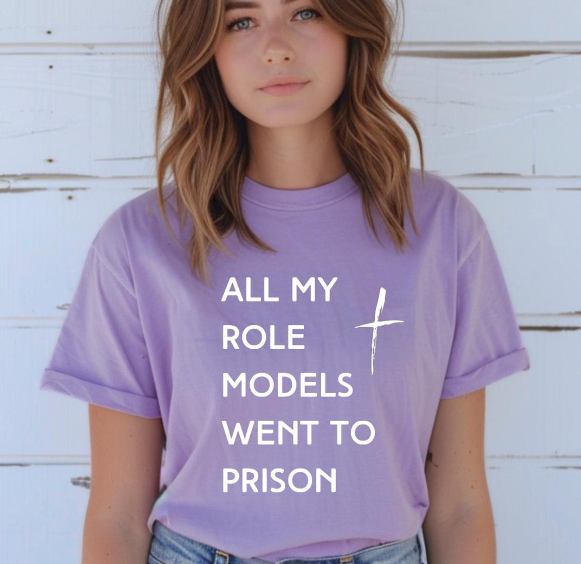 Lavender crewneck t-shirt that says, “all my role models went to prison” with a cross. 