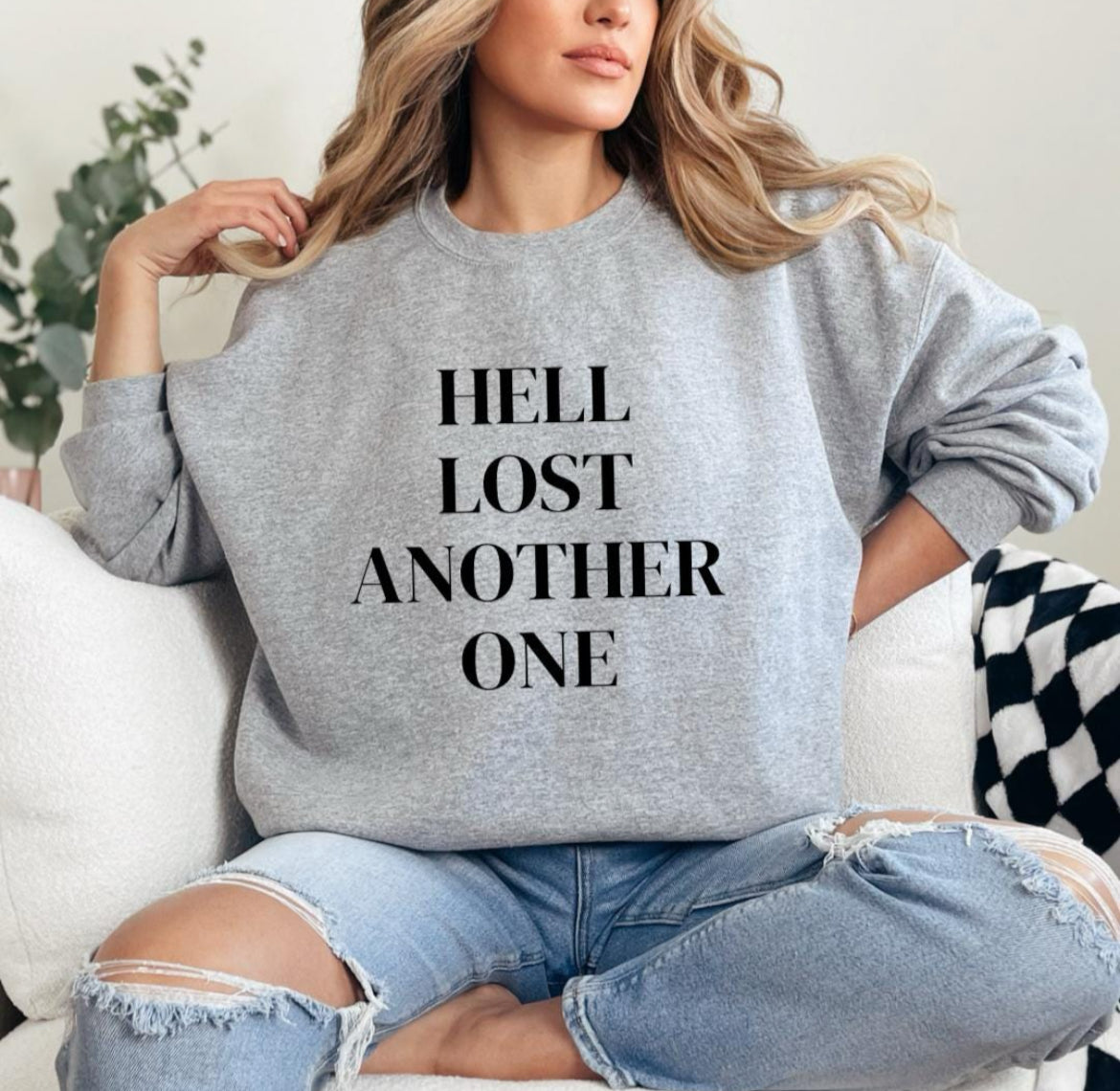 Light sporty gray crewneck sweatshirt that says, "Hell lost another one."