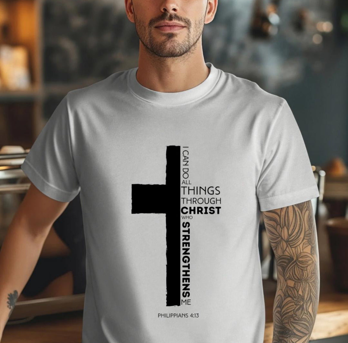 Grey crewneck t-shirt with a cross where half of the cross is the Bible verse Philippians 4:13. It says, “I can do all things through Christ who strengthens me.”