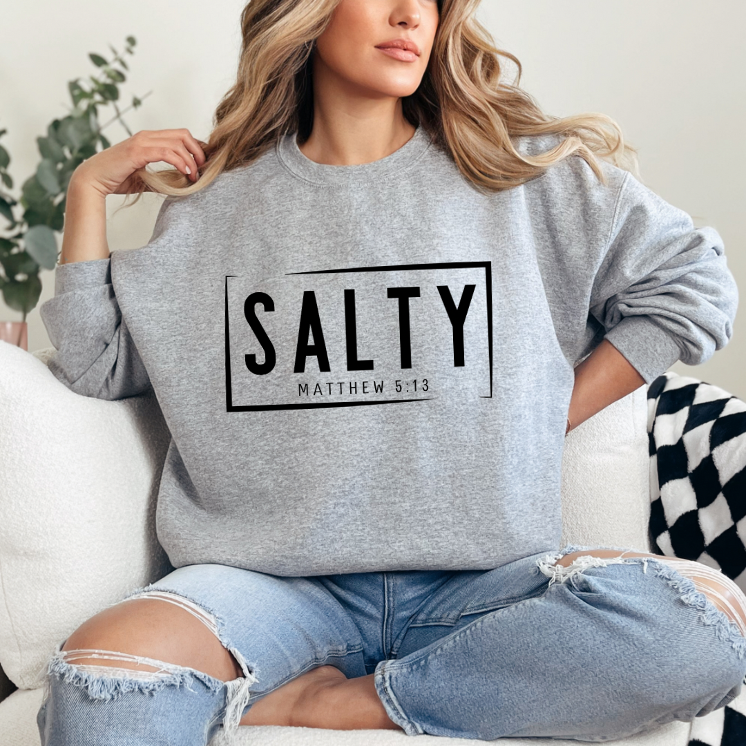 Grey crewneck sweatshirt that says, “SALTY” in large capital letters. Underneath in smaller letters it says, “Matthew 5:13.”