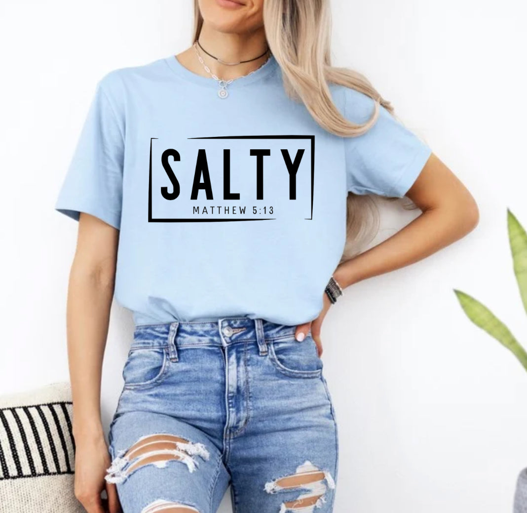 Baby blue crewneck t-shirt that says, “SALTY” in large capital letters. Underneath in smaller letters it says, “Matthew 5:13.” Christian Apparel