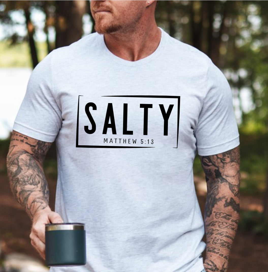 Ash white crewneck t-shirt that says, “SALTY” in large capital letters. Underneath in smaller letters it says, “Matthew 5:13.” Christian Apparel