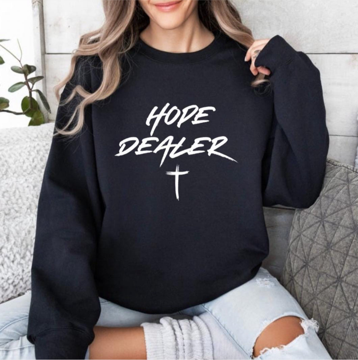 Black crewneck sweatshirt that says, “Hope dealer” in graffiti style writing with a cross. 