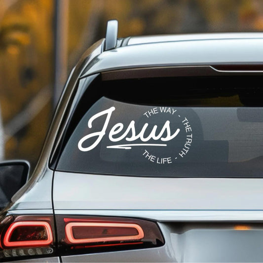 Car decal that says, “Jesus - the way, the truth, the life.” The word “Jesus” is in large cursive letters. The other words are in print and round the ending of “Jesus”.