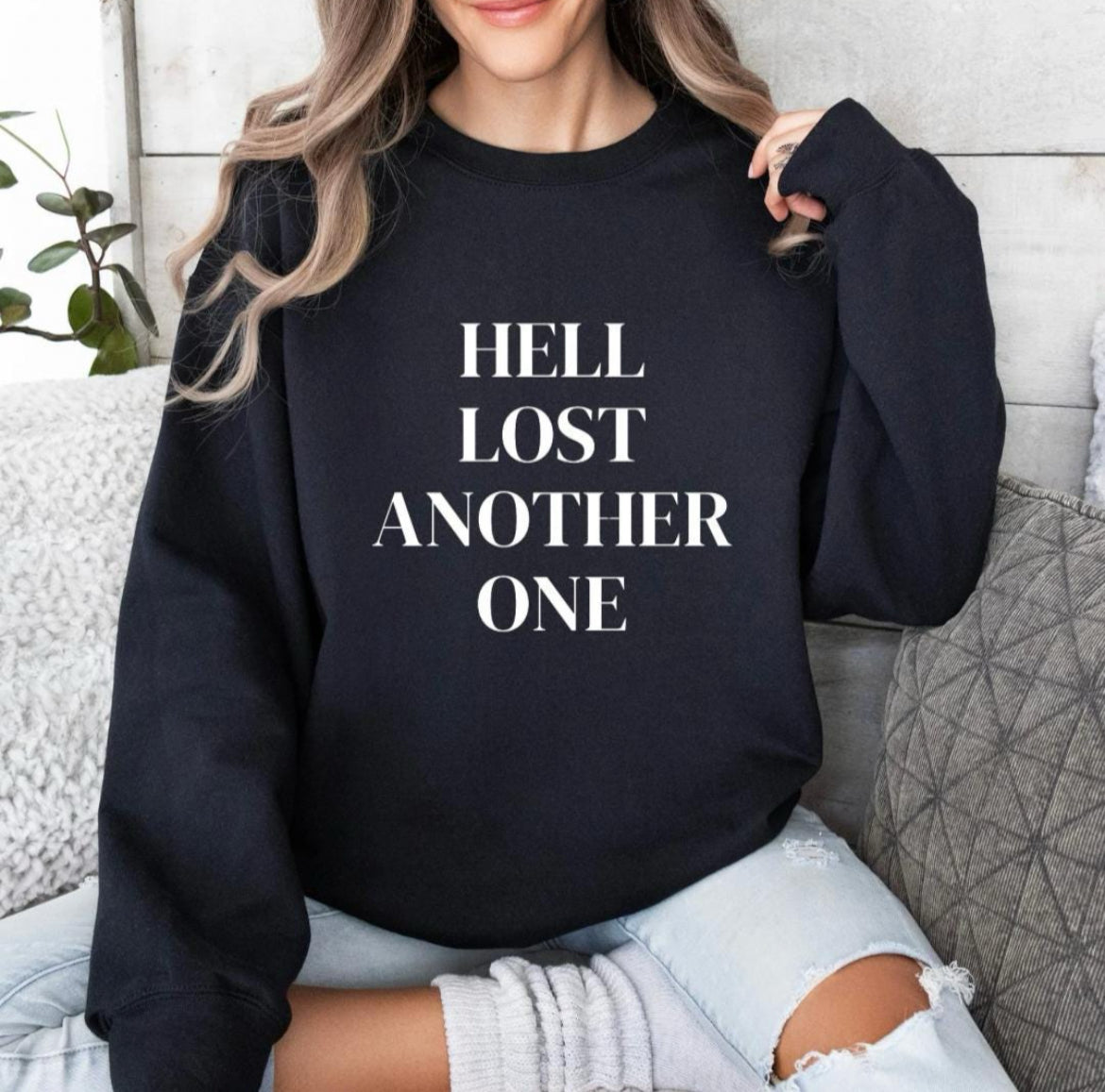 Black crewneck sweatshirt that says, "Hell lost another one" on the front.