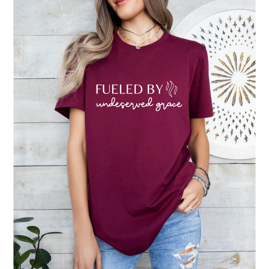 Maroon crewneck t-shirt that says, “Fueled by undeserved Grace”.