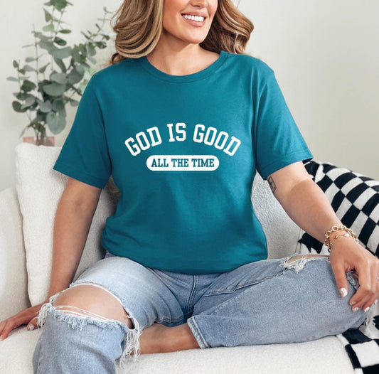 Deep teal crewneck t-shirt that says, “God is good all the time”.