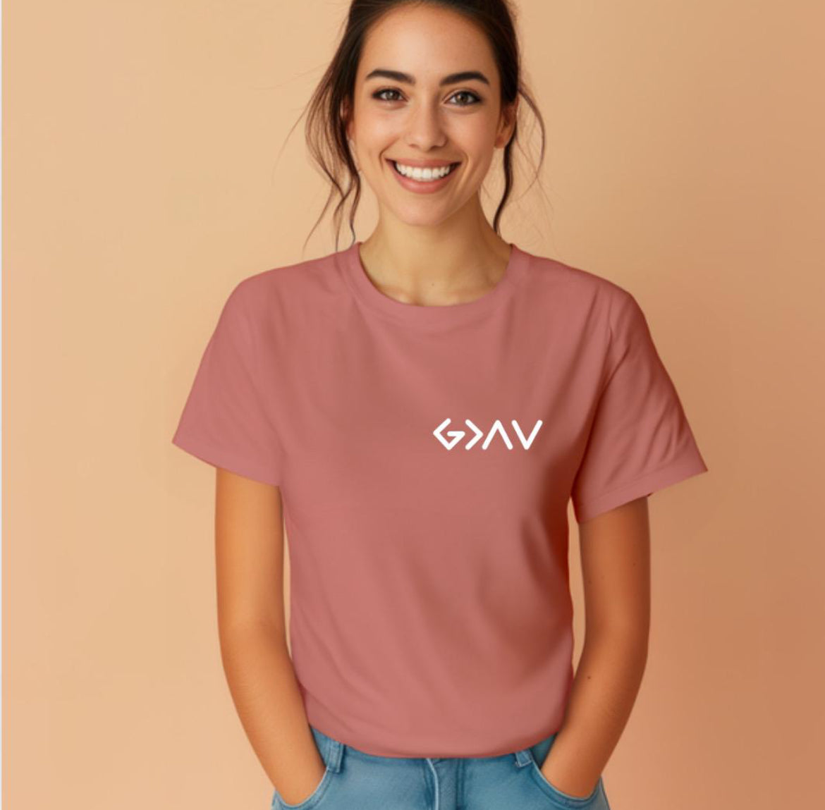 Mauve crewneck t-shirt with a cross on the back that has the symbol “God is greater than the highs and lows” as the bottom part of the cross.  The front has the same symbol in the upper left-hand corner.