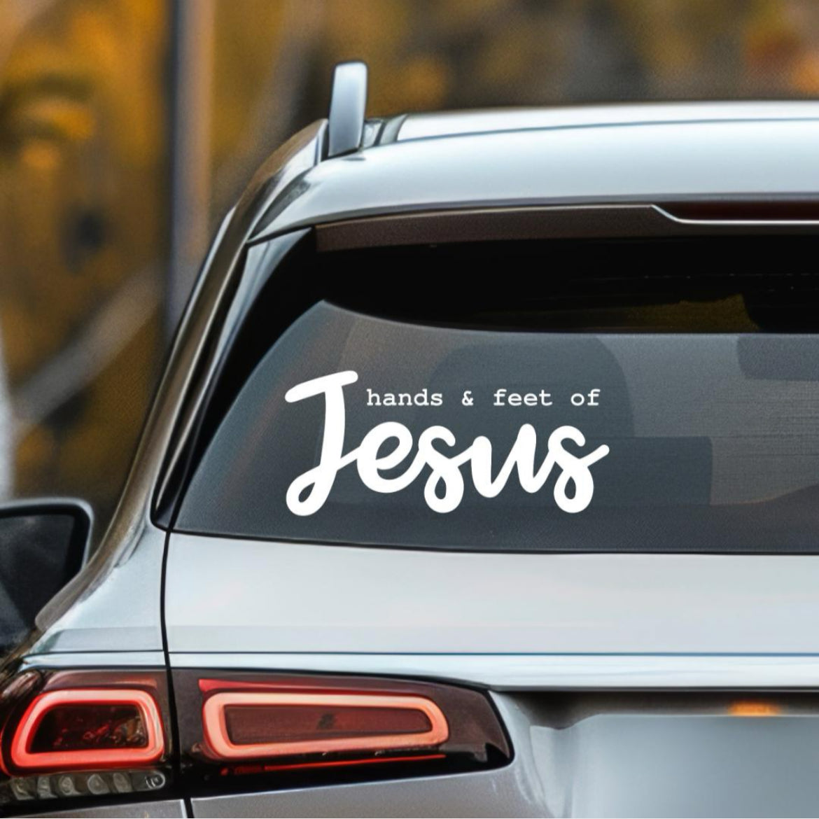 Car decal sticker that says, “hands and feet of Jesus”. The word “Jesus” is in large cursive letters. 