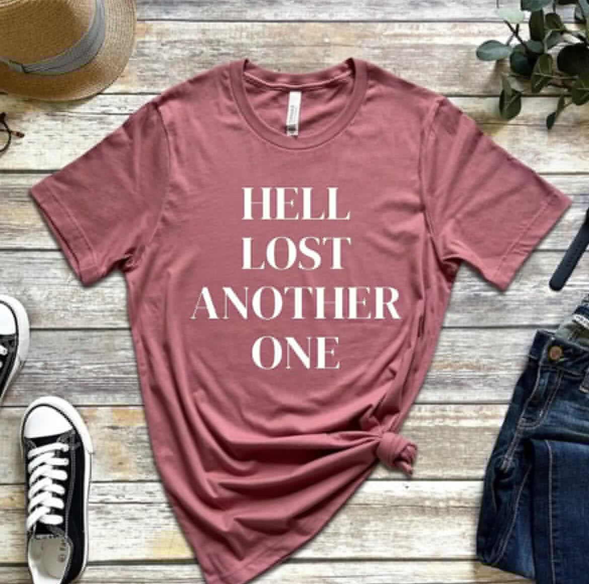 Mauve crewneck t-shirt that says, “Hell lost another one.”